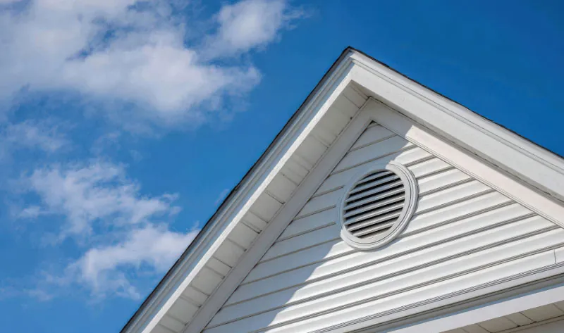 Close-up of a gable exhaust vent on a Virginia home showing proper attic ventilation under clear blue skies.