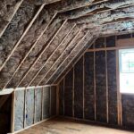 Fiberglass batt insulation installed along the sloped ceiling and walls of a residential attic by Toler Insulating.