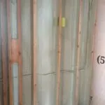 Closed-cell spray foam insulation applied between wood framing studs in a finished wall section.