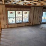 Living room under construction with closed-cell spray foam insulation applied to the walls and ceiling for improved energy efficiency.