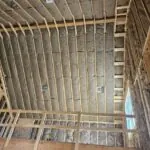 Fiberglass insulation installed in the ceiling and walls of a loft area during new home construction.