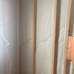 Close-up of closed-cell spray foam insulation applied between wall studs during residential construction.