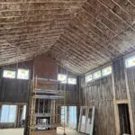 Vaulted great room under construction with fiberglass batt insulation installed in ceiling cavities.
