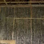 Brown Knauf EcoBatt fiberglass insulation installed between wall studs for superior energy efficiency and noise reduction.
