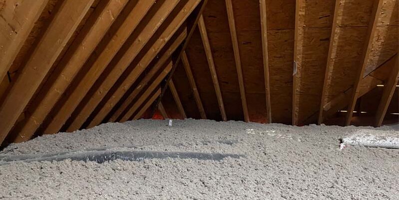 A home attic featuring a thick, even layer of professional blown-in cellulose insulation installed by Toler Insulating to improve energy efficiency and year-round comfort.