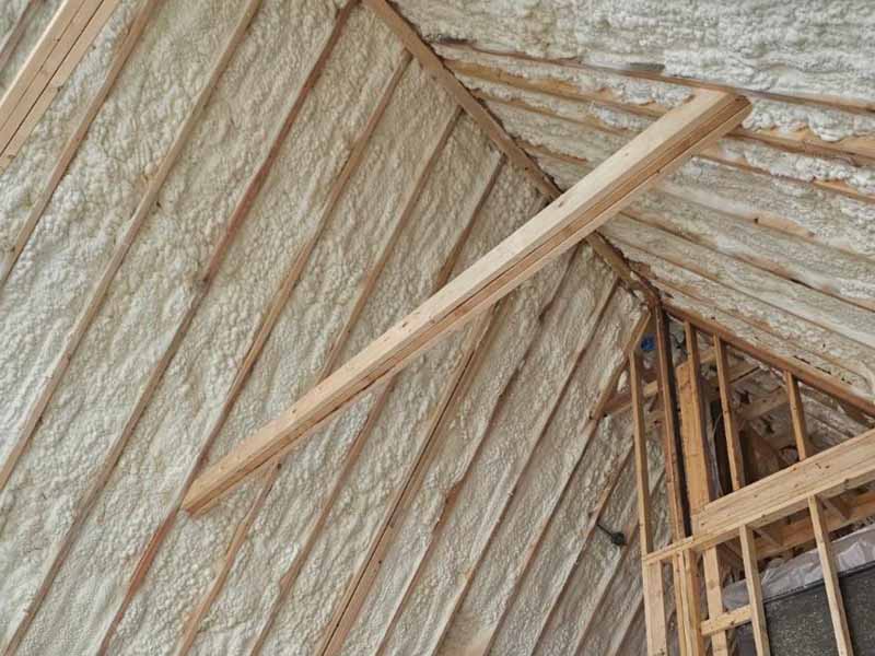 Open-cell spray foam insulation applied to a vaulted attic roofline with loft framing.