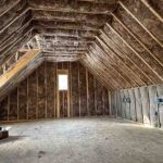 Toler Insulating fiberglass batts installed between roof rafters, gable end wall, and knee walls of an unfinished bonus room in Lynchburg, VA.