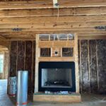 Toler Insulating fiberglass batts installed in exterior wall cavities on both sides of a framed fireplace in a new construction home in Lynchburg, VA.